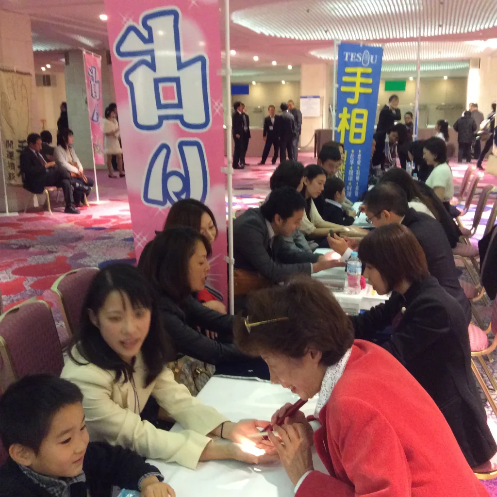 イベント会場で来場者の手相を鑑定するスクール修了生